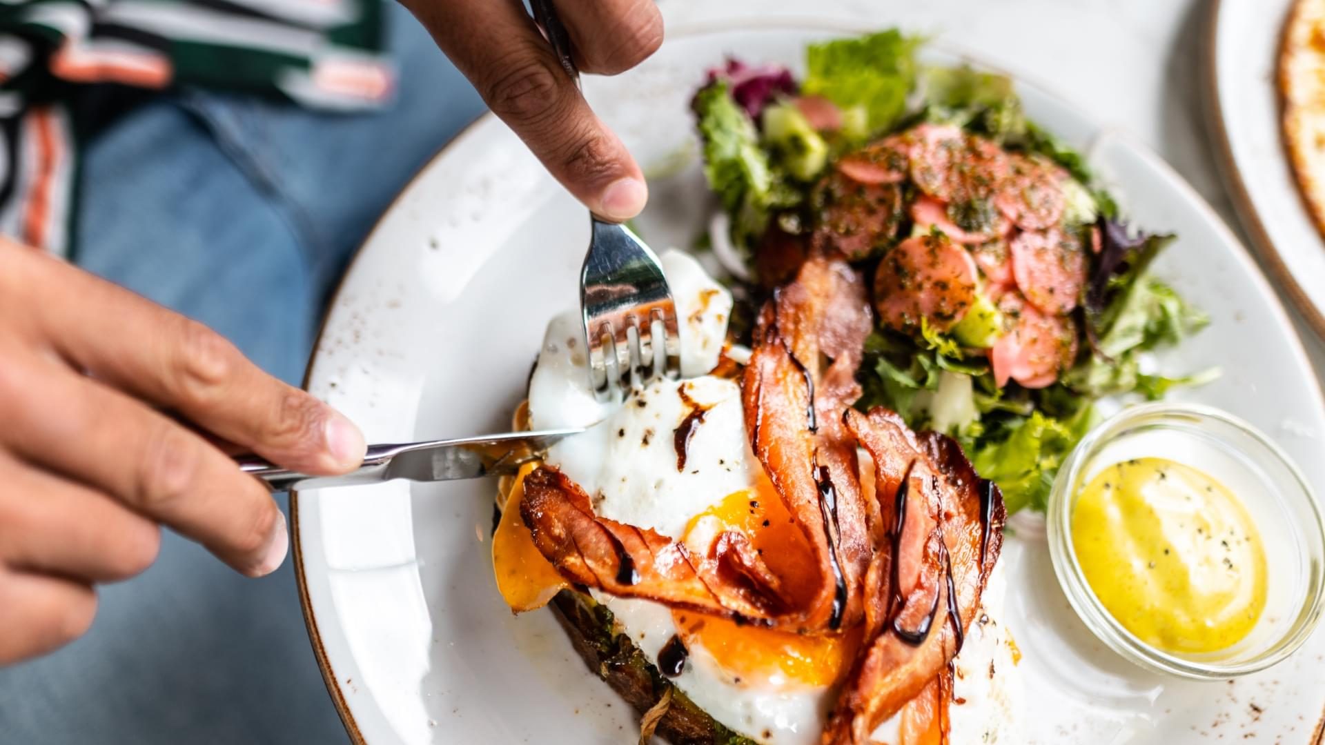 A loaded baked potato with fried egg and bacon and a salad.